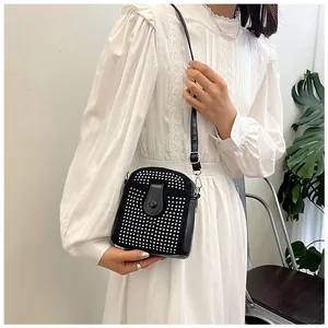 Detail of a mini black crossbody bag featuring silver rhinestones and a metal zipper