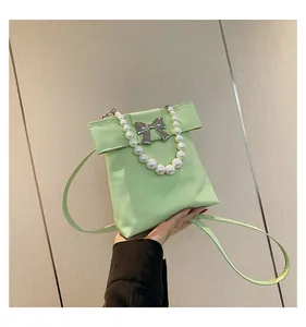 Close-up of mint green handbag with pearl handle and silver bow metal decoration