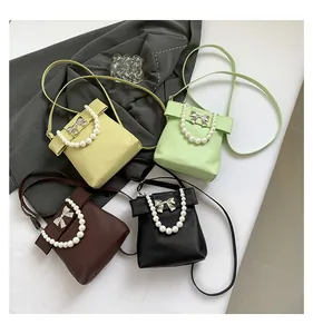 Detail of four colorful mini pearl bags with metal bow decorations and leather straps