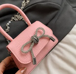 Detail van roze leren handtas met glinsterende strass-strik en zilveren ketting