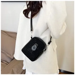 Detail of a mini black rhinestone crossbody bag paired with a white blazer for contrast