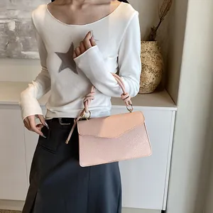 Pink PU leather handbag with knotted handle and envelope flap on a fashion model