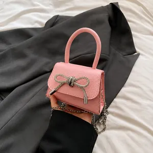 Detailopname van roze handtas van litchi-leer met een schitterende strik van stras
