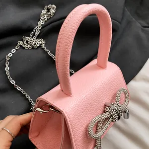 Detailopname van de roze litchi-textuur mini-tas met een luxe strass-strik decoratie
