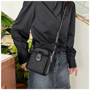 Close-up of stylish black crossbody phone bag with silver stud rivets and leather strap