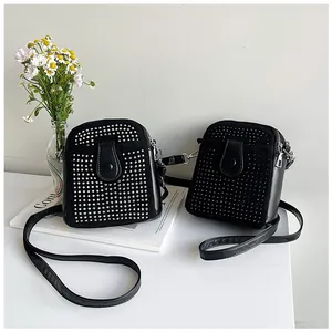 Detail of black mini crossbody bags with silver and black rivet studs on a white table