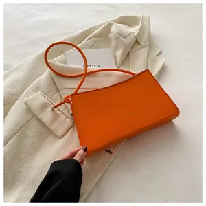 Dettaglio della borsa baguette arancione acceso con scritta fashion su blazer