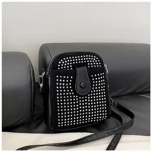 Detail of black crossbody mini bag with silver studs and smooth PU leather texture