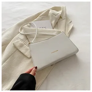 Dettaglio della borsa baguette bianca con scritta FASHION gialla e tracolla sottile