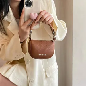 Dettaglio mini borsa in pelle martellata marrone con borchie a stella in metallo argento