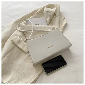 Dettaglio borsa baguette in pelle PU bianca con scritta Fashion dorata e tracolla
