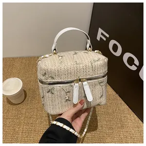 Detailed straw vanity case bag with green floral embroidery and gold hardware chain