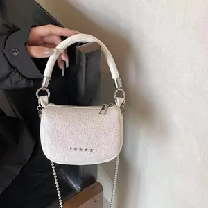Dettaglio borsa a mezzaluna bianca con trama litchi e decorazioni di stelle argentate