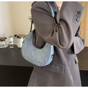 Detail view of light blue crescent bag with washed leather texture and metal buckle