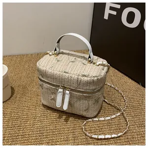 Detail of floral embroidery on a beige woven straw box bag with golden chain strap