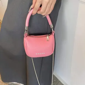Dettaglio borsa rosa in pelle litchi con elegante catena di perle e anello metallico