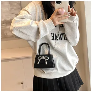 Gedetailleerde spiegelselfie van een zwarte mini crossbody tas met strass strik en ketting