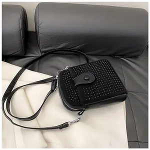 Close-up of black rhinestone mini crossbody bag with silver zipper and leather strap