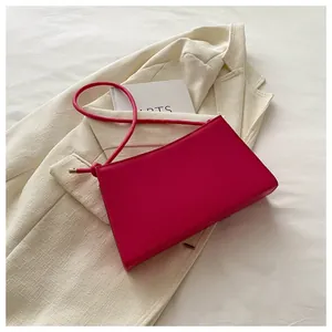 Dettaglio della borsa baguette in pelle rosa con fibbia metallica su un blazer beige