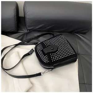 Detail of black crossbody bag featuring silver studs and double zipper compartments