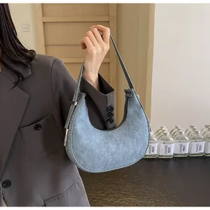 Detail of gray crescent shoulder bag with silver zipper and fine matte texture
