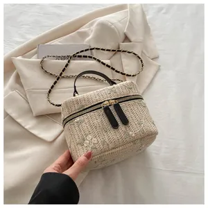 Detailed embroidery of light green and pink floral motifs on a beige woven box bag