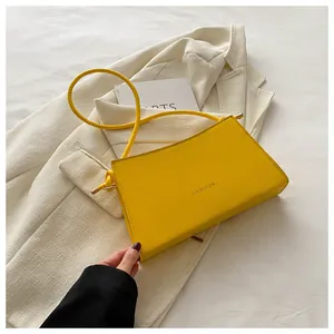 Dettaglio borsa a tracolla gialla con scritta Fashion su sfondo di tessuto bianco