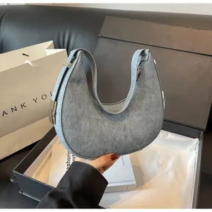 Close-up of a minimalist grey suede crescent hobo bag with elegant silver hardware details