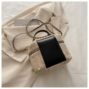 Detail of lace woven straw handbag with floral embroidery and gold chain strap