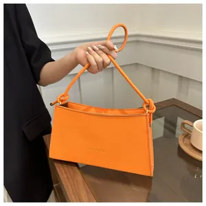 Dettaglio di una borsa in finta pelle arancione con manico a corda sottile e stampa fashion