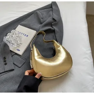 Detail of a metallic gold crescent hobo bag resting on a stylish grey blazer fabric