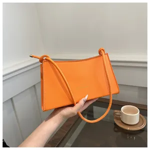 Dettaglio della borsa a tracolla arancione con logo FASHION e sottili spalline annodate