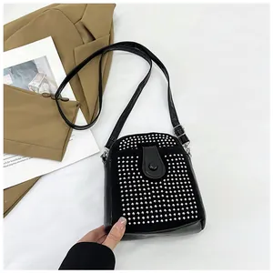 Detail view of black rhinestone mini crossbody bag with silver studs on white background