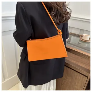 Dettaglio della borsa baguette arancione brillante con scritta fashion e tracolla annodata