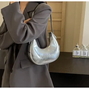 Close-up of metallic silver crescent hobo bag with smooth texture on a model shoulder