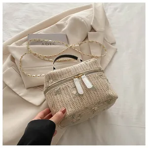 Close-up of cream woven straw bag featuring floral embroidery and gold chain strap
