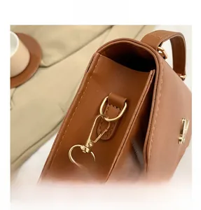 Detail of golden metal hardware and fine stitching on a brown leather handbag