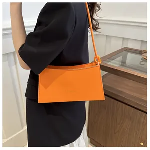Dettaglio della borsa sottobraccio arancione alla moda con logo FASHION dorato