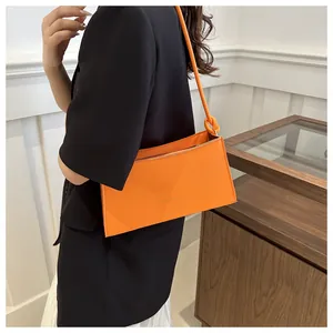 Dettaglio borsa baguette arancione con stampa dorata e tracolla con nodo alla moda