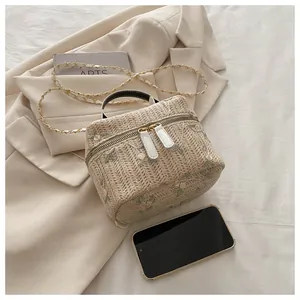 Close-up of beige straw woven handbag with floral embroidery and gold chain strap