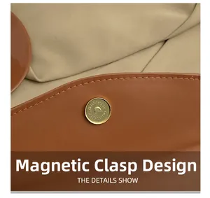 Close-up of golden magnetic snap button on brown leather handbag with neat stitching