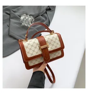 Close-up of vintage mini crossbody bag with logo pattern and gold clasp