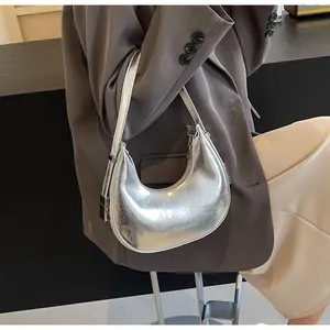 Detailed view of silver crescent underarm bag with metallic crackle texture and strap buckle