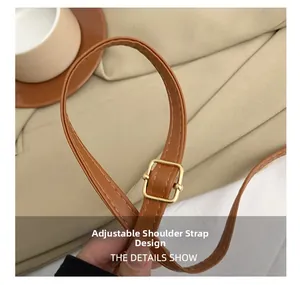 Detail of adjustable brown leather shoulder strap with elegant gold metal buckle hardware