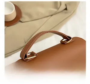 Detail of brown leather bag handle with gold rings and white butterfly ornament
