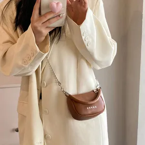 Mini borsa a tracolla marrone con catena argentata e dettagli a stella indossata da modella