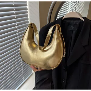 Detailed macro view of gold metallic crescent hobo bag with silver buckle and smooth texture
