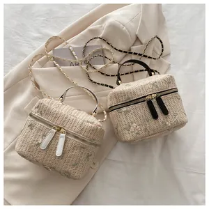 Detail of embroidered straw bucket bag with gold chain strap and dual zipper closure