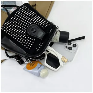 Flat lay showing interior capacity of black studded crossbody bag with daily essentials