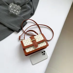 Retro canvas crossbody bag with tan leather trim and gold hardware on white background